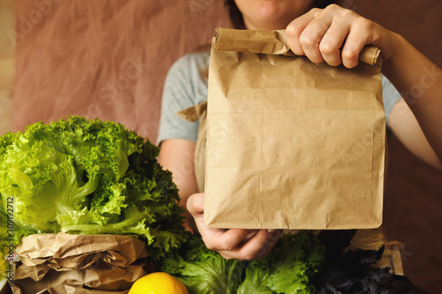 Organic vegetables in eco bag in market. Woman seller giving craft paper bag with products in organic food store.  Healthy nutrition, Zero Waste, Lifestyle. Mock up blank blank template for, design