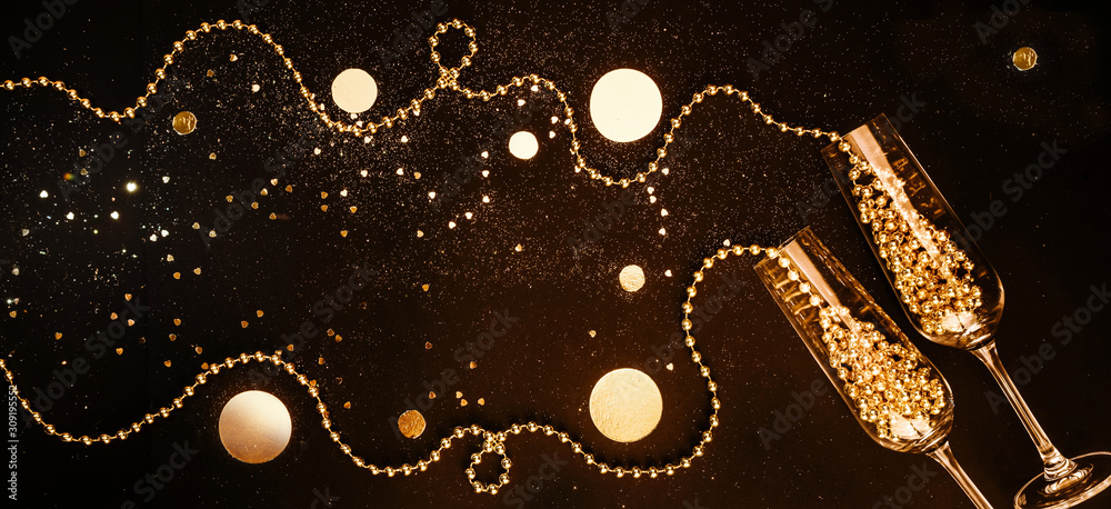 Champagne glasses filled with golden decorations on a black shiny background. Celebration minimal Christmas party. Banner Copy Space. Flat lay Champagne glasses filled with golden decorations on a black shiny background. Celebration minimal Christmas party. Banner Copy Space. Flat lay