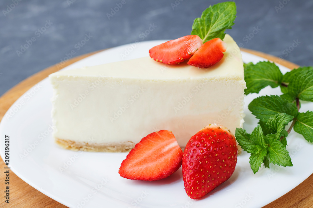 Classic cheesecake New York sliced Piece of cheesecake with fresh strawberries and mint on a white plate on a classic blue background. Close up. Selective focus. Copy space Classic cheesecake New York sliced Piece of cheesecake with fresh strawberries and mint on a white plate on a classic blue background. Close up. Selective focus. Copy space