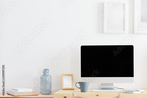 Cozy empty workplace at home or in the office is a desk and a computer with a large empty black screen standing next to the mug. Remote and freelance work concept. Advertising space © Rithor