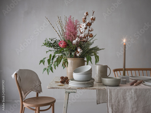 Tisch wird festlich gedeckt zur Weihnachts- und Winterzeit mit großer Blumendekoration