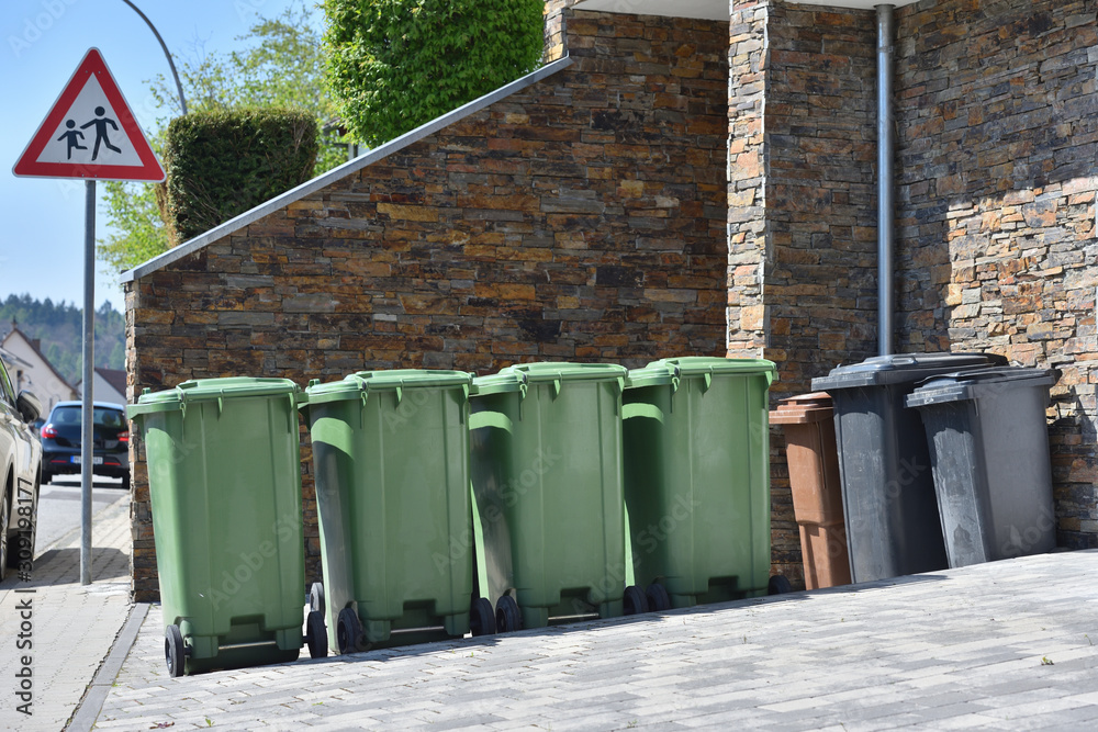 Green trash cans are standing against the wall. Garbage containers for sorting garbage in a European city Green trash cans are standing against the wall. Garbage containers for sorting garbage in a European city