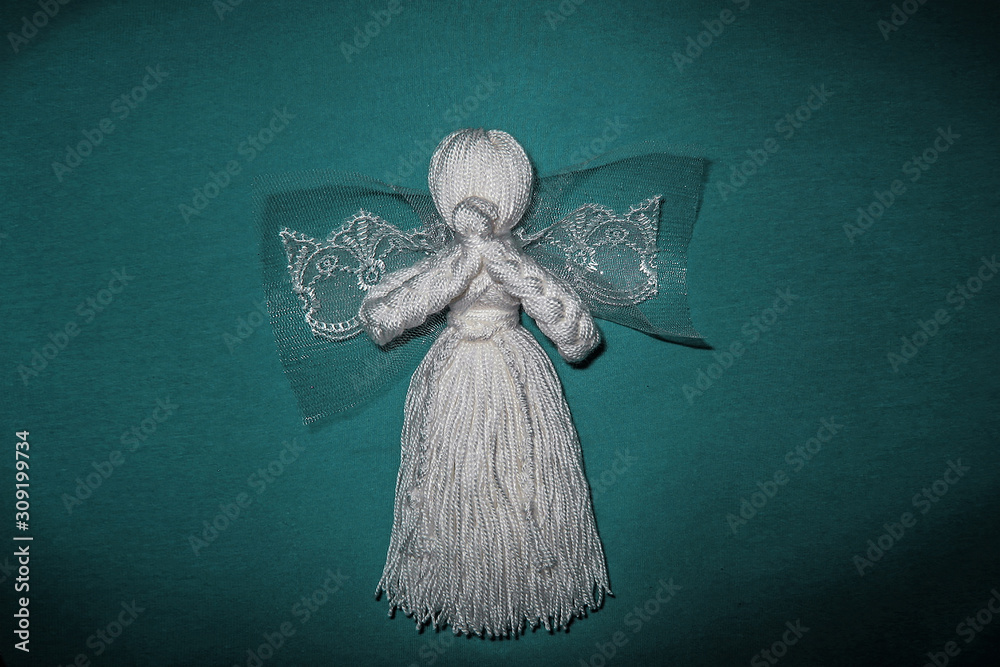 White angel with wings on cyan background. Prayed thread doll as a symbol of love, charity and faith. Christmas and New Year decoration design