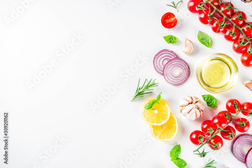 Fototapeta Naklejka Na Ścianę i Meble -  Cooking background with spices, vegetables and herbs fresh basil, rosemary, tomato, garlic, onions, lemon on a white kitchen table. Layout top view copy space. Healthy ingredients for cooking