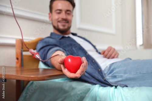 Foto Young man making blood donation in hospital, focus on hand