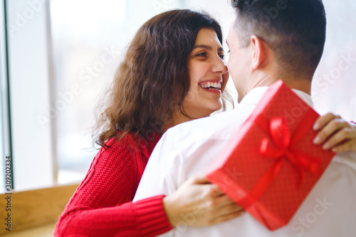 Wallpaper Mural Cheerful couple with gift in hands enjoying together on Christmas eve. Winter holidays. A young loving couple celebrating Valentine's Day in the restaurant. Lovers give each other gifts.  Torontodigital.ca