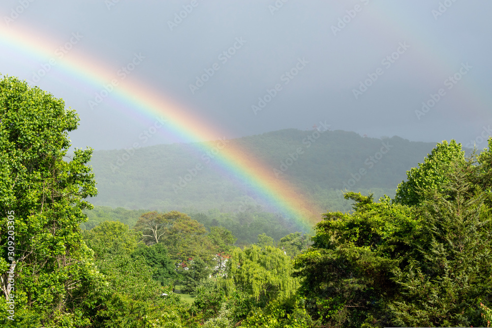 A bright rainbow is seen over the green landscape in the mountains of Virginia. A bright rainbow is seen over the green landscape in the mountains of Virginia.