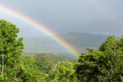 A bright rainbow is seen over the green landscape in the mountains of Virginia.