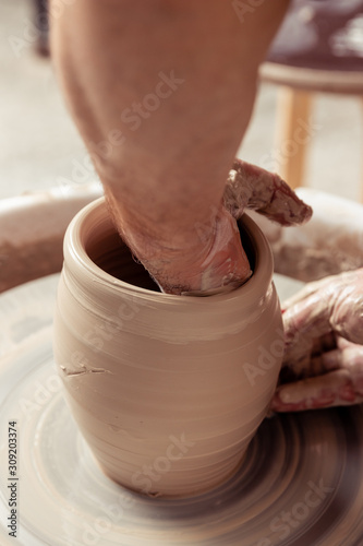 Potter making a jar pot of white clay on the potter's wheel circle in studio, concept of creativity and creativity, vertical photo