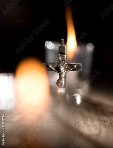 Photography Metal cross and candles on dark background