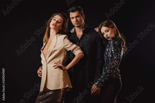 attractive and stylish women and handsome man hugging isolated on black