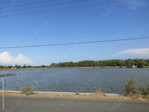 A view of a natural salt evaporation pond or tambak garam in village of Sidoarjo region. Traditional home industry with artificial shallow ponds designed to produce from sea water or water brines. photo