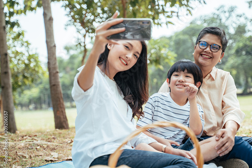 The concept of family relaxed activity in holiday.Happy Asian family mother son and grandmother enjoy picnic time at the park,spending time and have fruits in the park,lifestyle in family holiday.