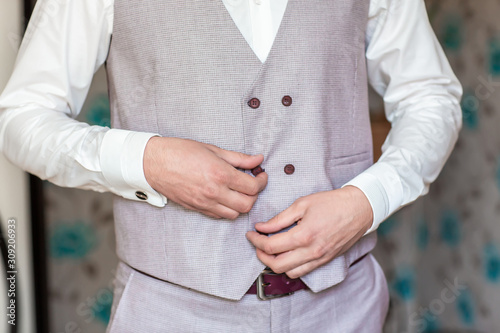 morning stylish groom - a young blond guy puts on a gray jacket. business man
