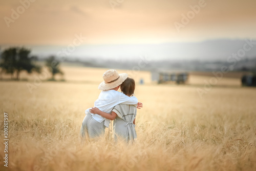 Two children a boy and a girl of preschool age walk together in a wheat field.