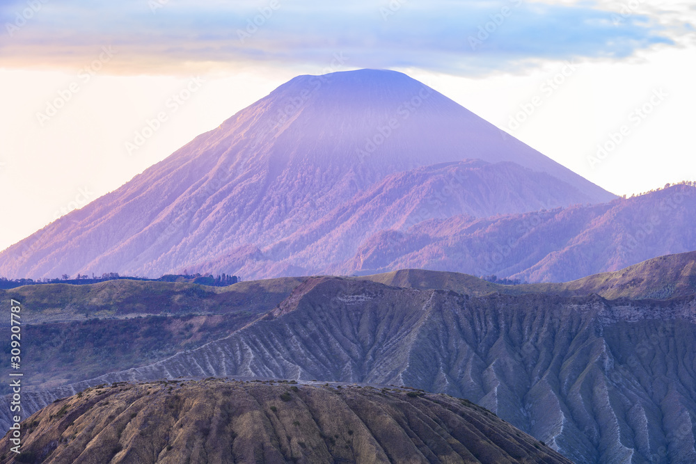 View from above, stunning view of the Mount Batok in the foreground and the Mount Semeru in the distance illuminated at sunrise, East Java, Indonesia.
