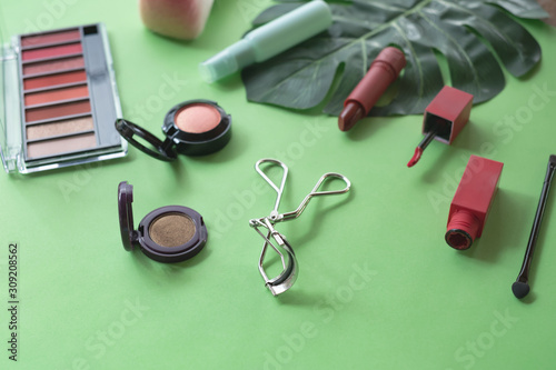 A collection of make up and cosmetic products arranged on a pastel green background.beauty concept.