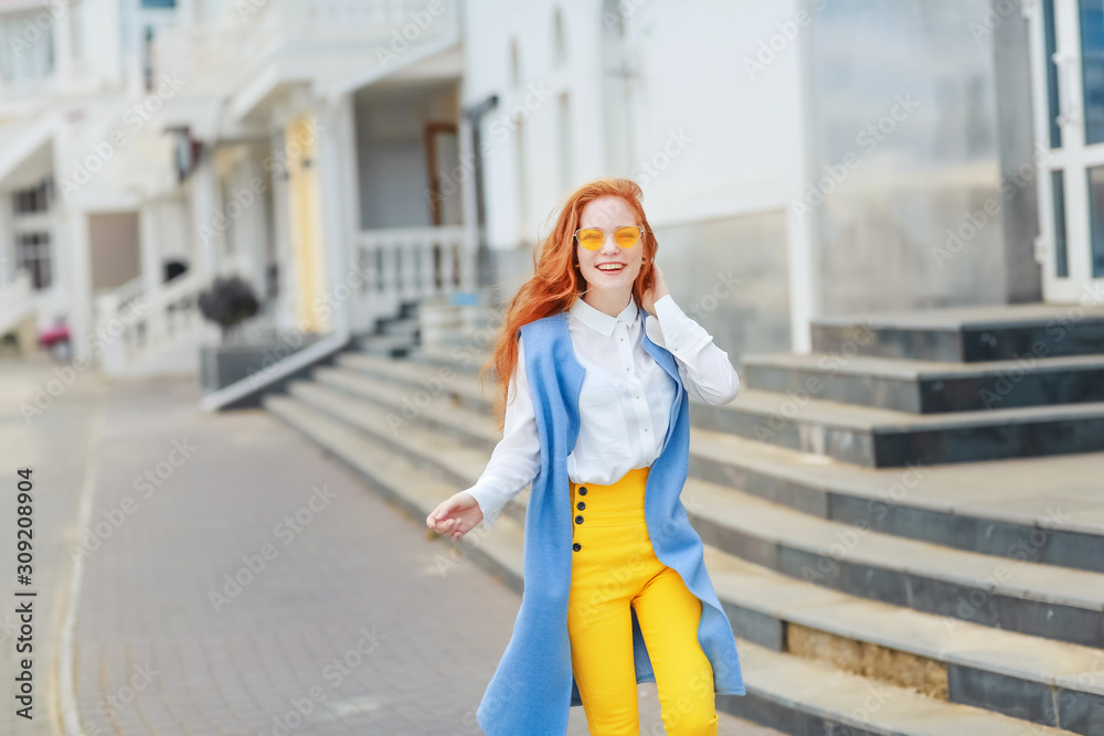 Obraz premium A student girl with a good mood goes near the building with stone steps.