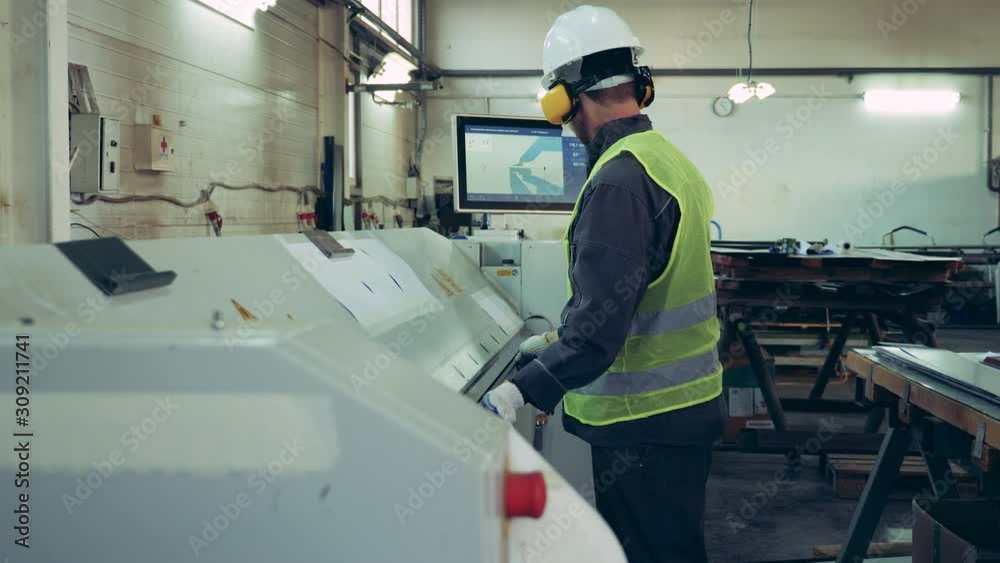 Factory worker is loading a metal sheet into the machine Factory worker is loading a metal sheet into the machine