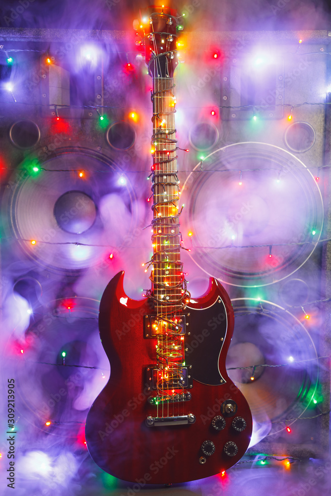 electric guitar with festive Christmas lights and music speakers in smoke