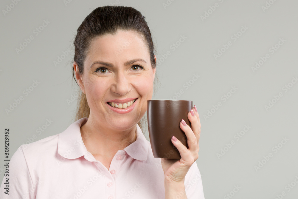 smiling middle-aged with a cup of fresh coffee or tea in her hand smiling middle-aged with a cup of fresh coffee or tea in her hand