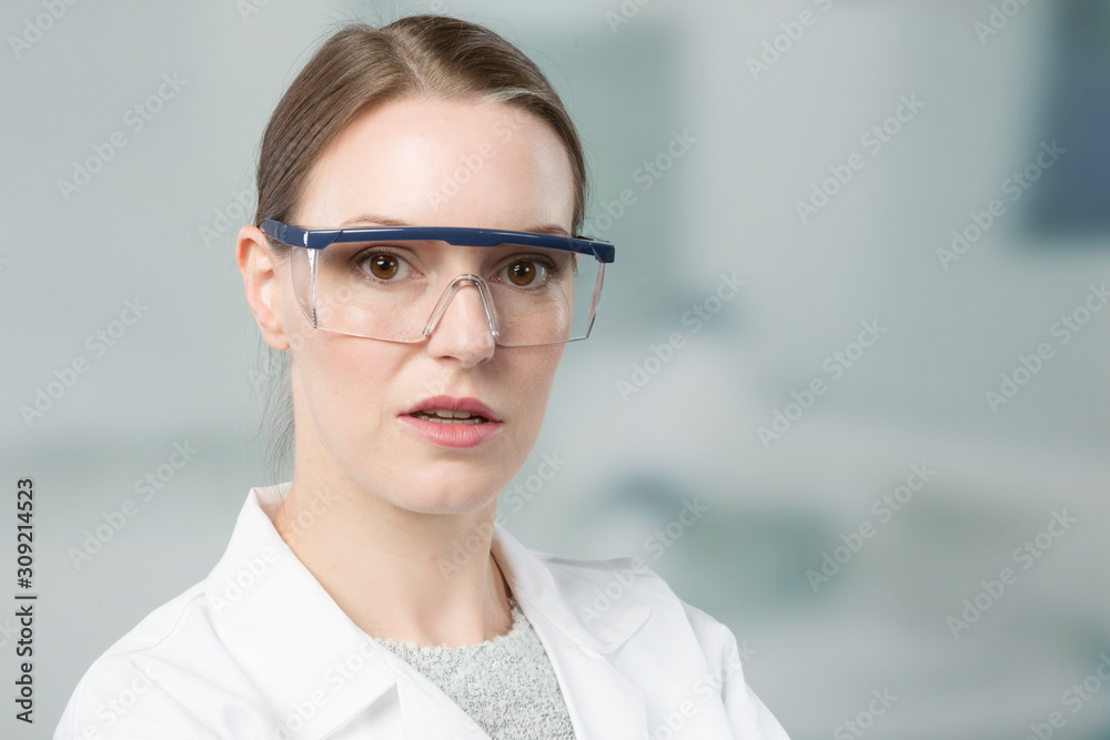 portrait of female scientist with and safety glasses in front of a laboratory