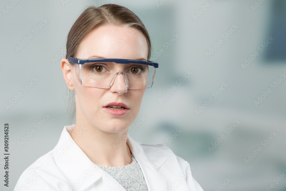 portrait of female scientist with and safety glasses in front of a laboratory portrait of female scientist with and safety glasses in front of a laboratory
