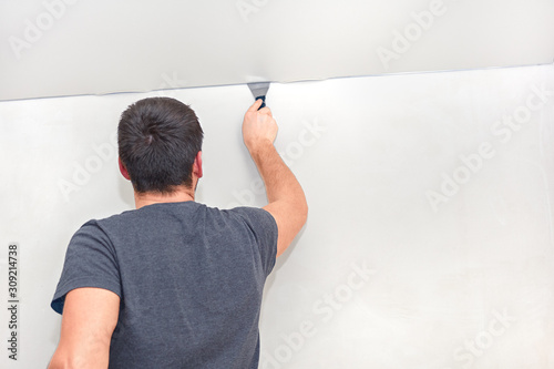 Installation of a stretch ceiling. Worker installs a stretch ceiling made of pvc vinyl film in the apartament.