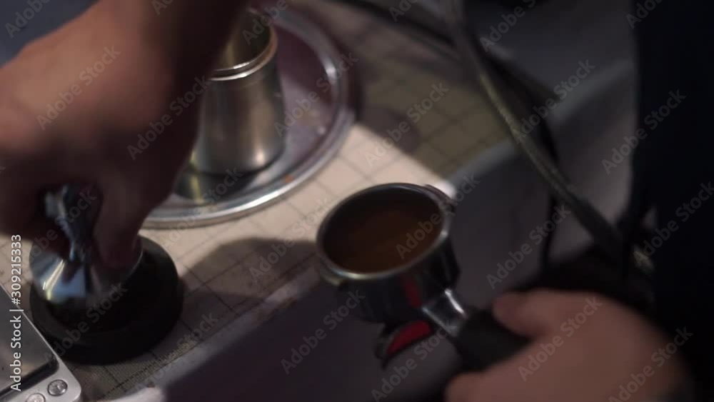 The barista is compressing the ground coffee into a basketball bag before entering an espresso machine The barista is compressing the ground coffee into a basketball bag before entering an espresso machine