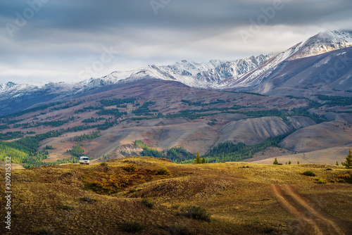 Dawn in the Chuy valley, a tourist minibus on a field road on a hillside. Russia, mountain Altai