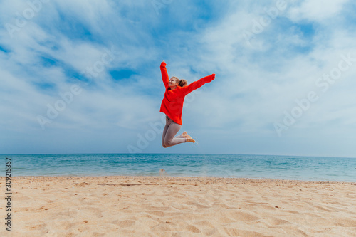 girl jumping on a sandy beach sea shore photo