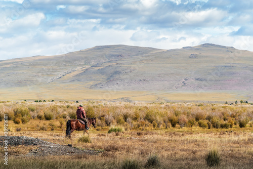A local resident riding a horse in the autumn Chuy valley. Russia, Altai Republic