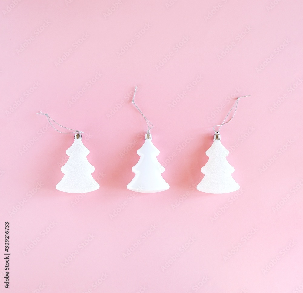 Three white christmas and new year trees on pastel pink background. Minimalistic holiday concept. Square, top view, flat lay.