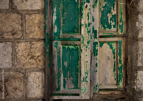 old green weathered door on a stone building © Erich