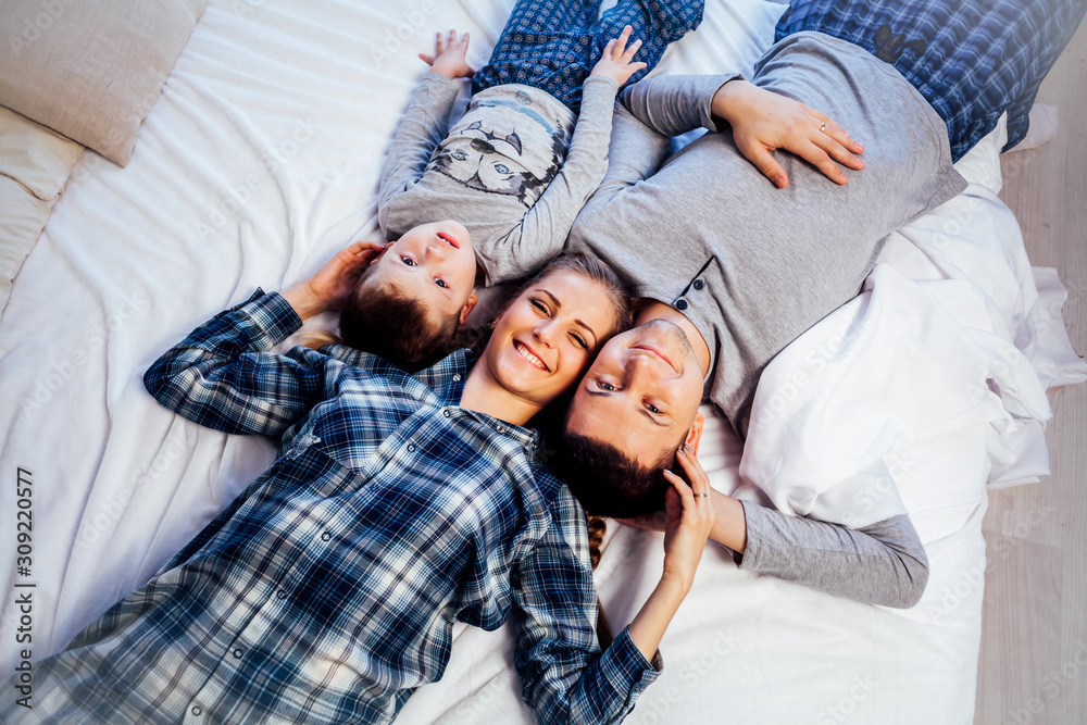 mom dad and son in the morning lying on the bed at home in a good mood