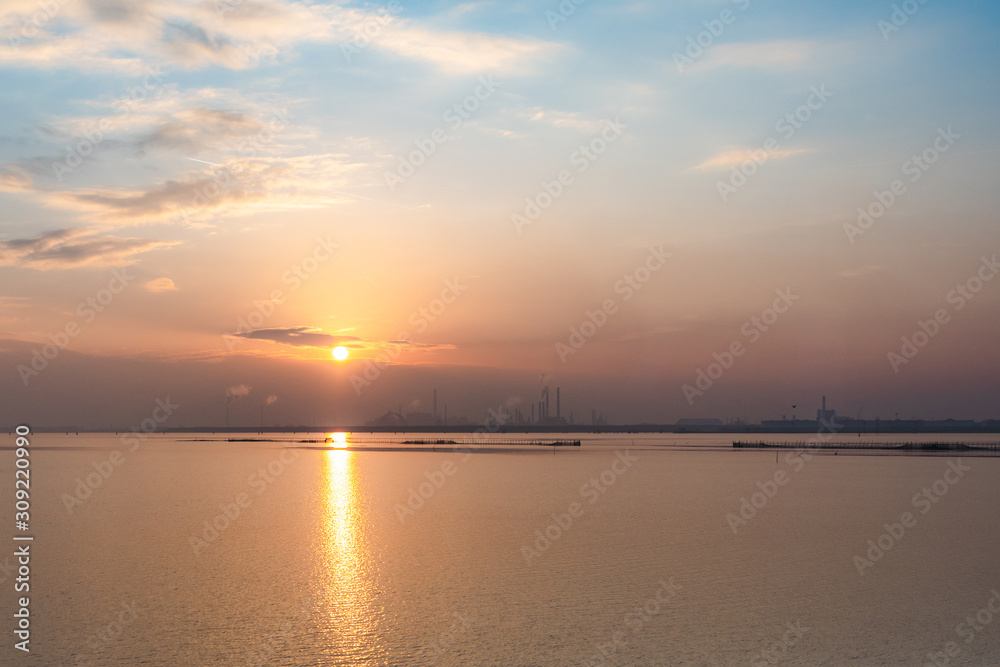 sunset over the venetian lagoon, ,smoke is coming out from some  industrial furnaces