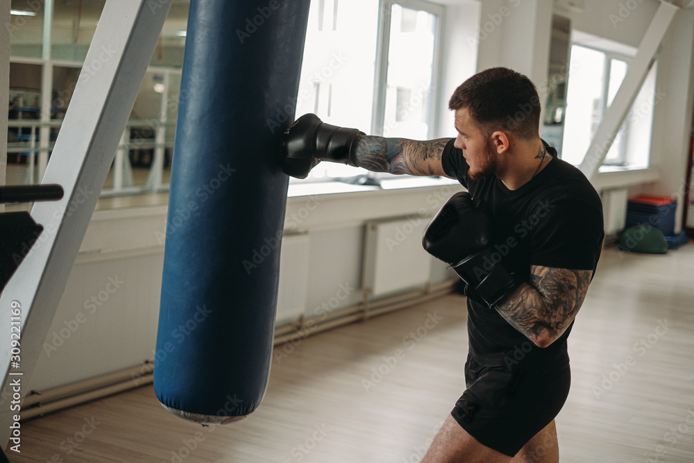 MMA and boxing training. Brutal, tattooed man boxing in a MMA training session in the gym.