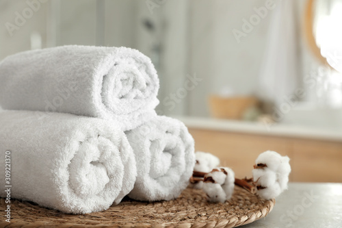 Clean rolled towels and cotton flowers on table in bathroom