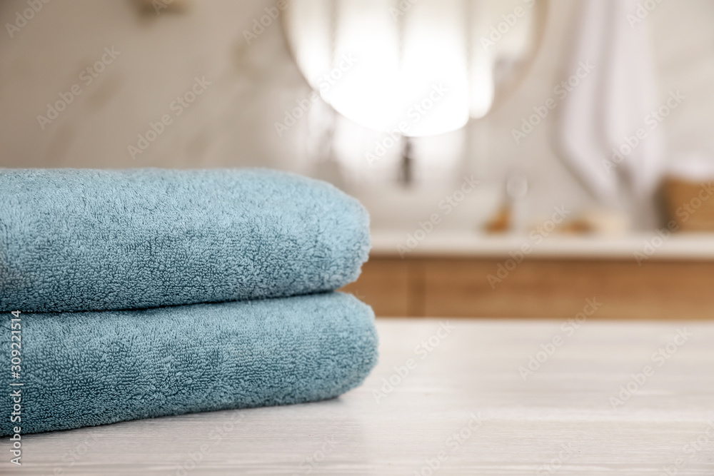 Stack of clean towels on white wooden table in bathroom. Space for text Stack of clean towels on white wooden table in bathroom. Space for text