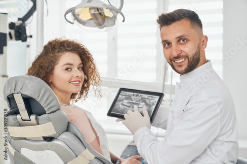 Male doctor and woman posing while sitting in dental office