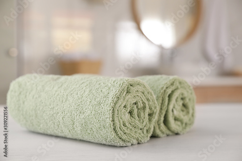 Clean rolled towels on white wooden table in bathroom