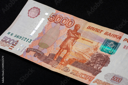 One Russian bill in the amount of 5000 rubles lies on a black background.