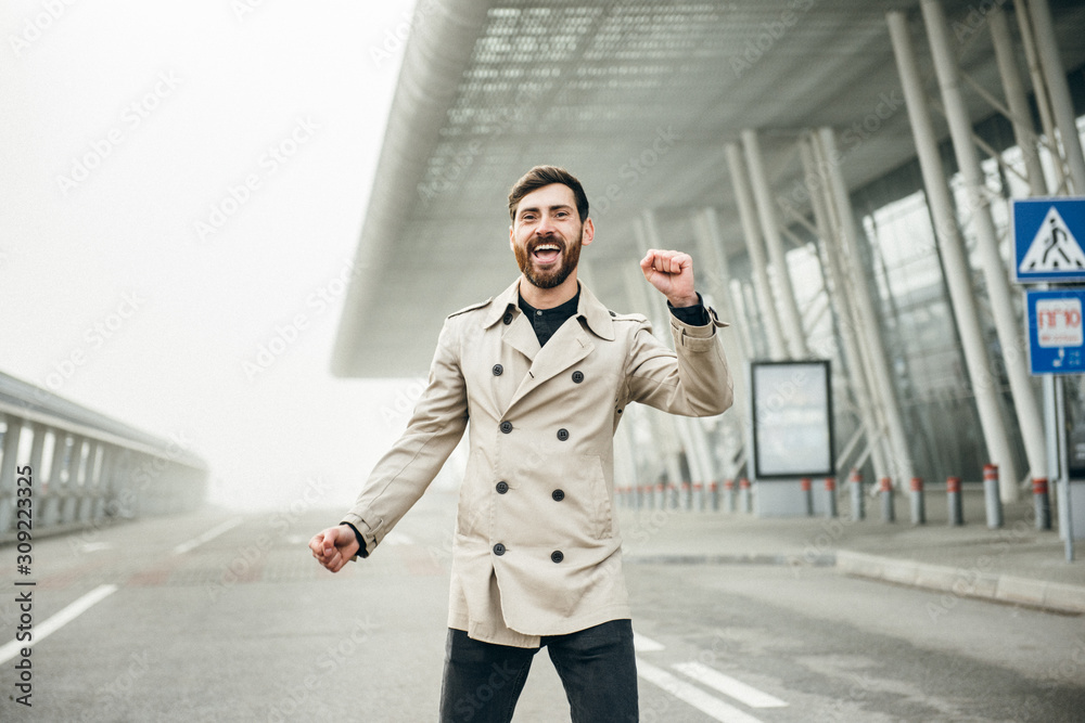Fototapeta premium Cheerful and Happy Businessman is Actively Dancing on a Street . He's Wearing a Grey Suit. Sunny Day.