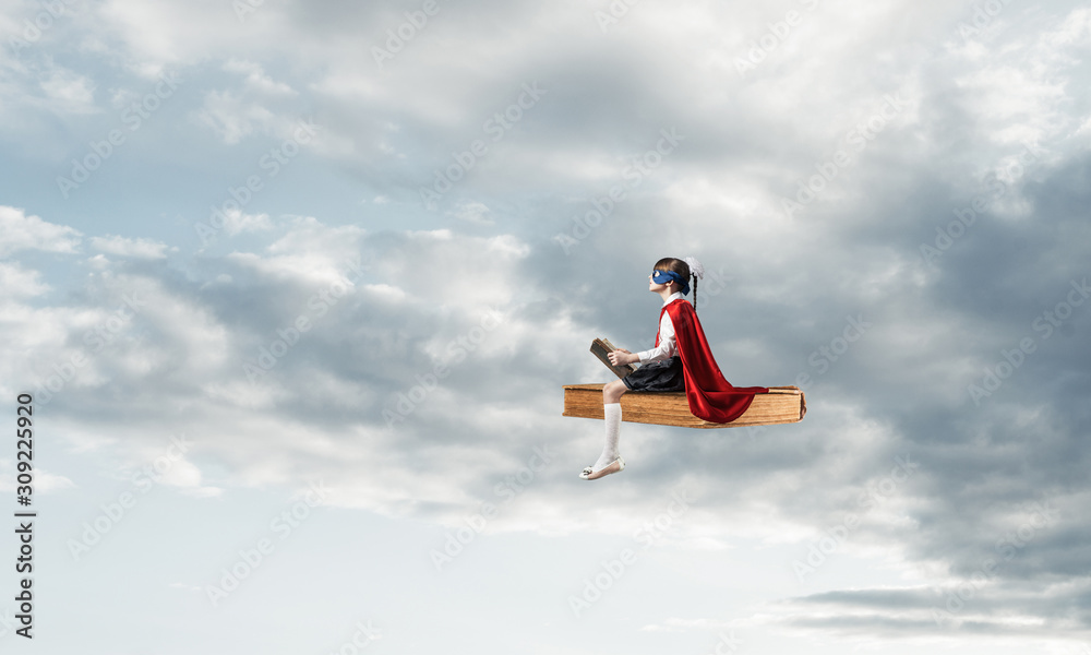 Girl power concept with cute kid guardian against cloudscape background Girl power concept with cute kid guardian against cloudscape background