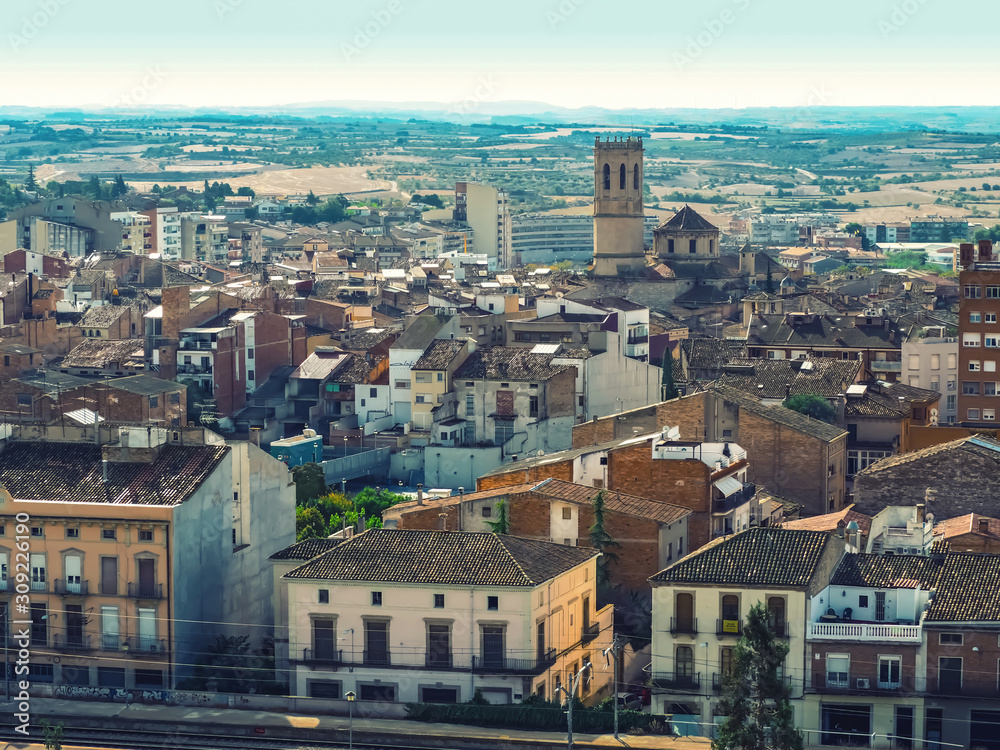Naklejka premium Tarrega, Spain - October 11, 2018: Beautiful urban panorama of the Catalan town of Tarrega - aerial view. Typical Spanish village with tiled roofs and the medieval chapel of Santa Maria de Alba church