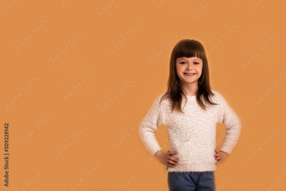 Looking concentrated and confident active child. girl smiling with happy emotion on face, enjoy life and her childhood. Positive people, lifestyle. Over orange background.