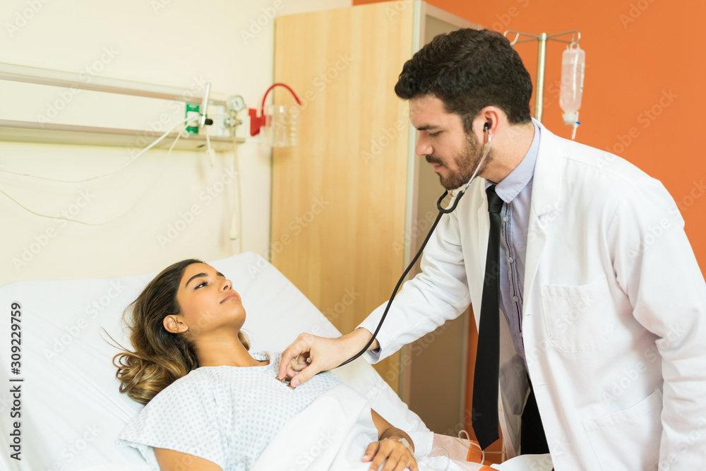 Fototapeta premium Male Healthcare Worker Treating Patient In Hospital