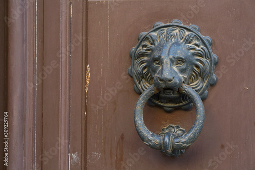 An old metal door knocker on a wooden door