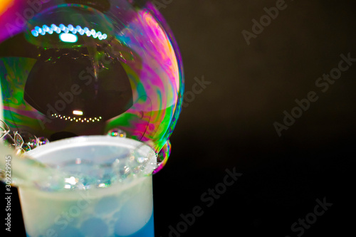 Abstraction. Soap bubbles on the water on a black background. The play of colors. Blurry multicolored bubbles. Close-up.