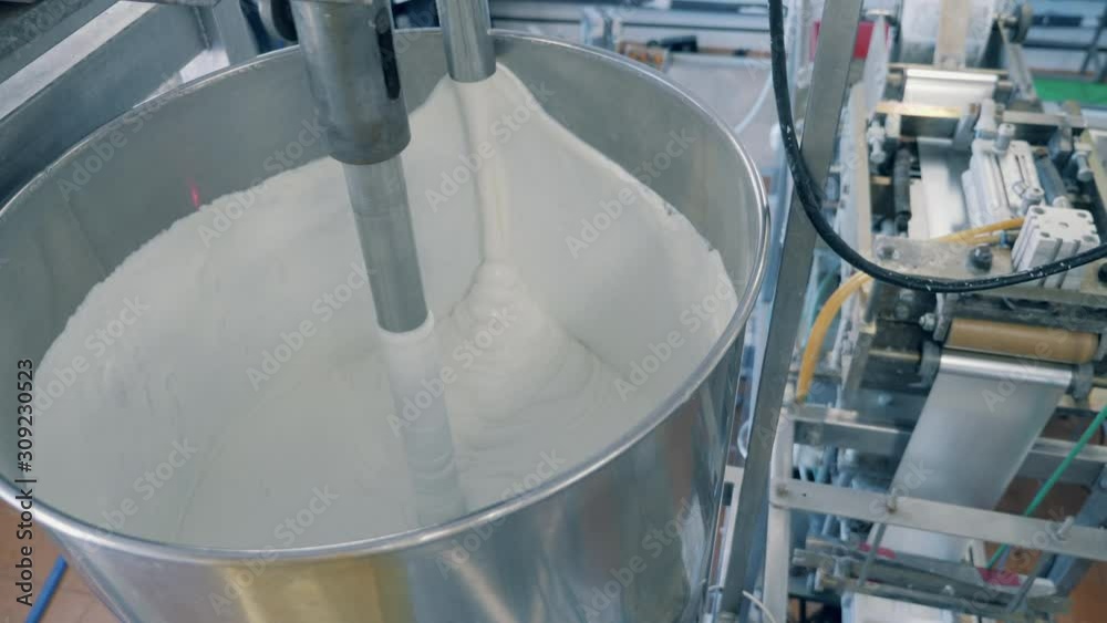 Metal machine stirs cream at a factory. Metal machine stirs cream at a factory.